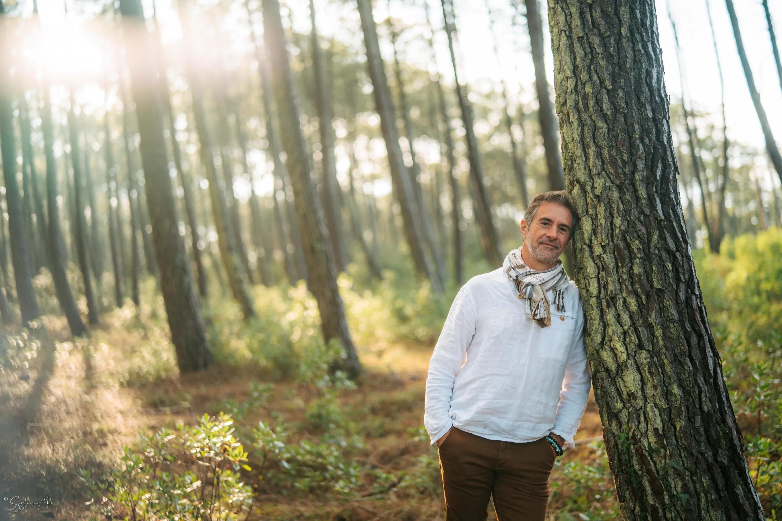 Pierre Lapoujade adossé à un arbre dans une forêt